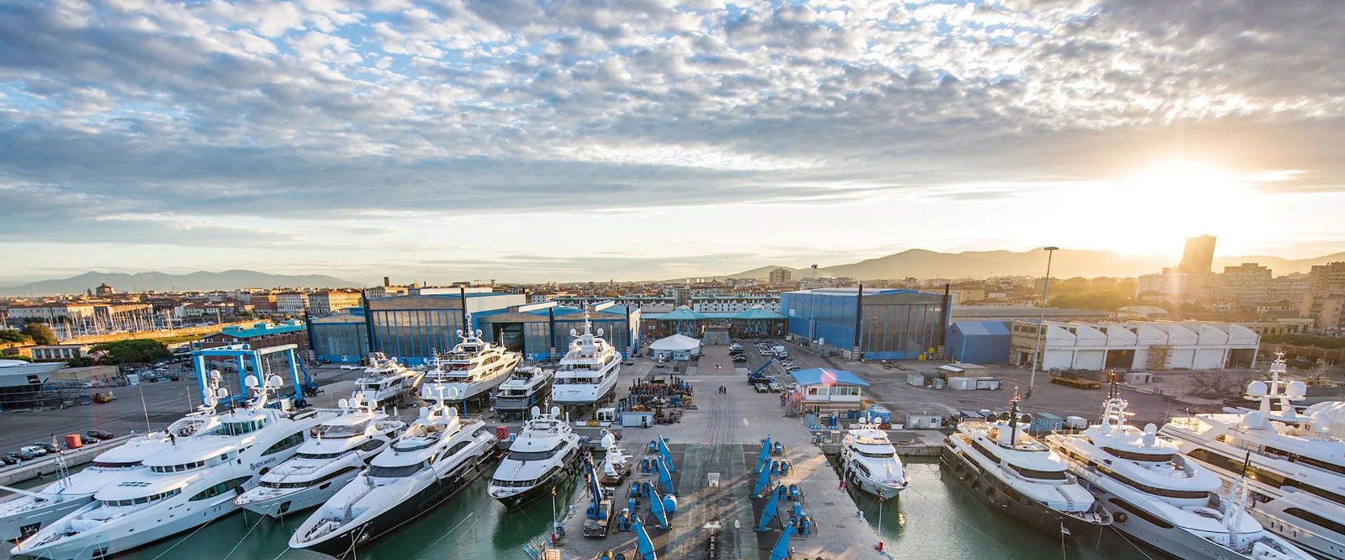 Benetti shipyard in Livorno at sunrise, superyachts alongside the yard halls