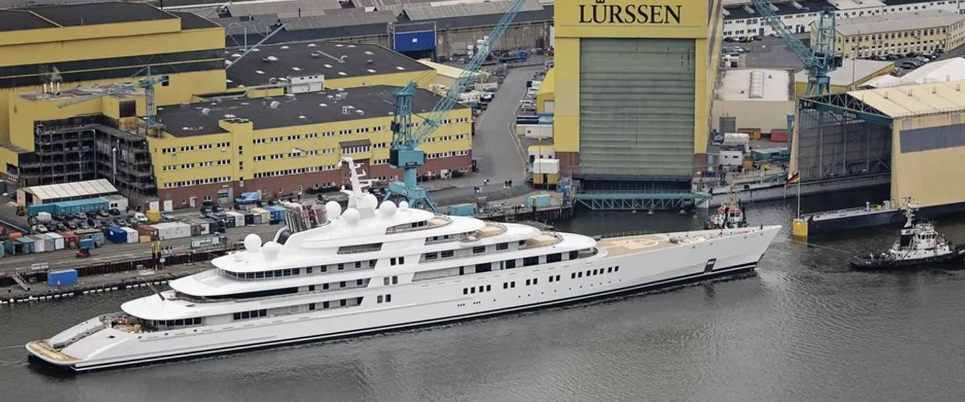 Lürssen shipyard in Bremen — the branded build hall and cranes with a superyacht under tow alongside